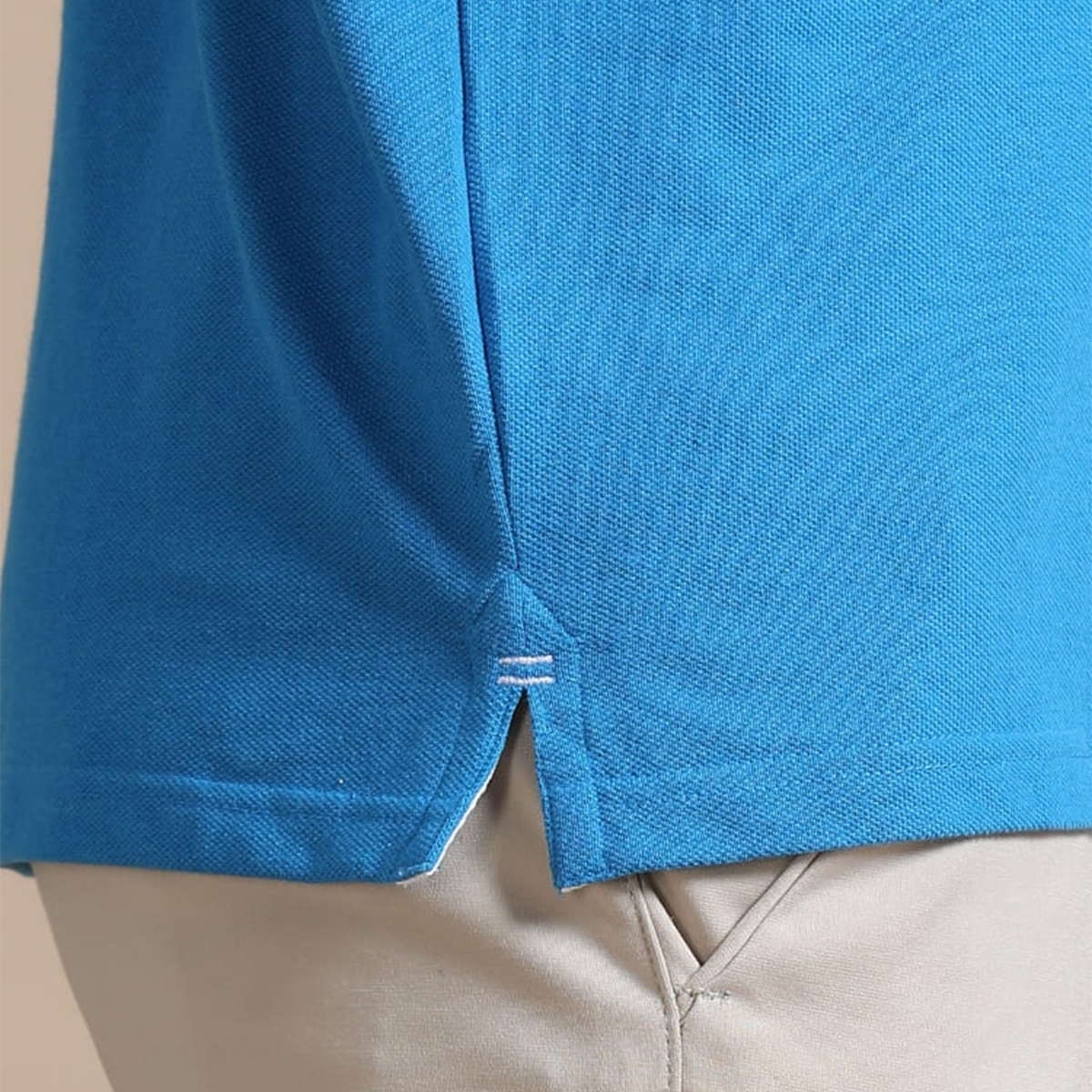 Close-up of side slit on aqua blue jacquard polo t-shirt, designed for better movement and comfort.